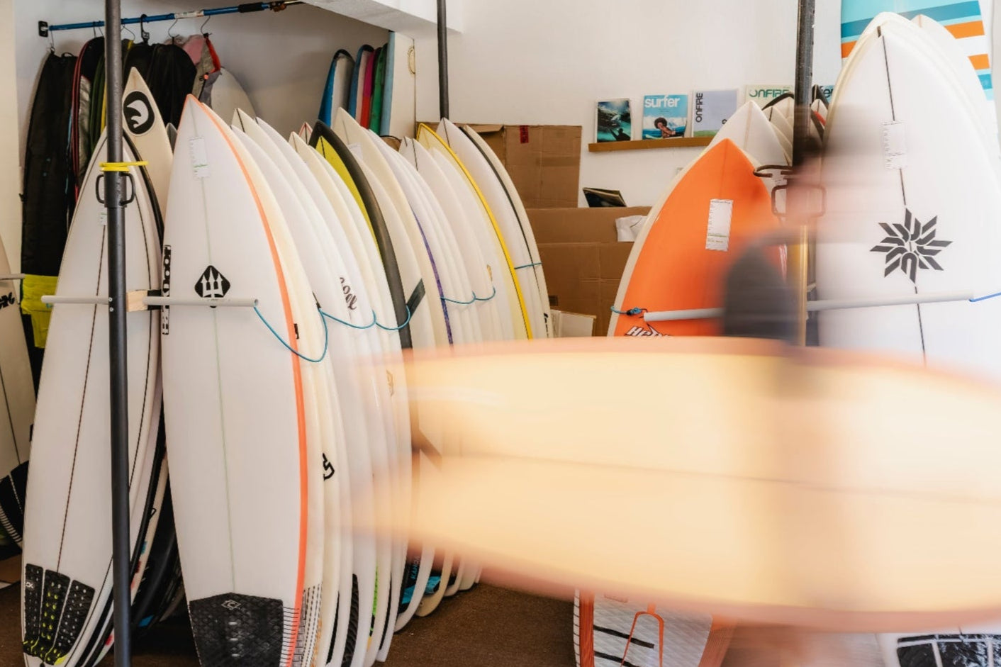 Surfboards on display in a store with a person walking by