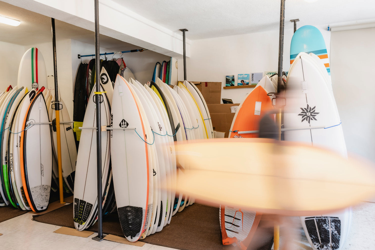 Surfboards on display in a store with a person walking by